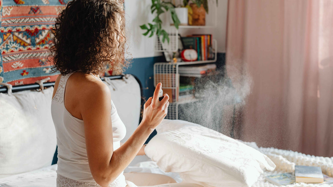 A woman spraying a DIY home scent spray in her living room, surrounded by cozy decor and plants, creating a calming atmosphere