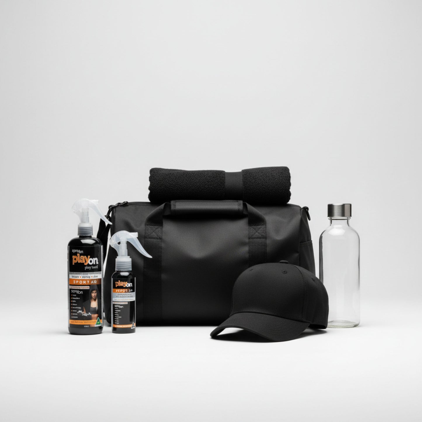 Black duffel bag with a cap, water bottle, and playon dup refill pack - playon spray refill and playon 80ml spray on a light grey background.