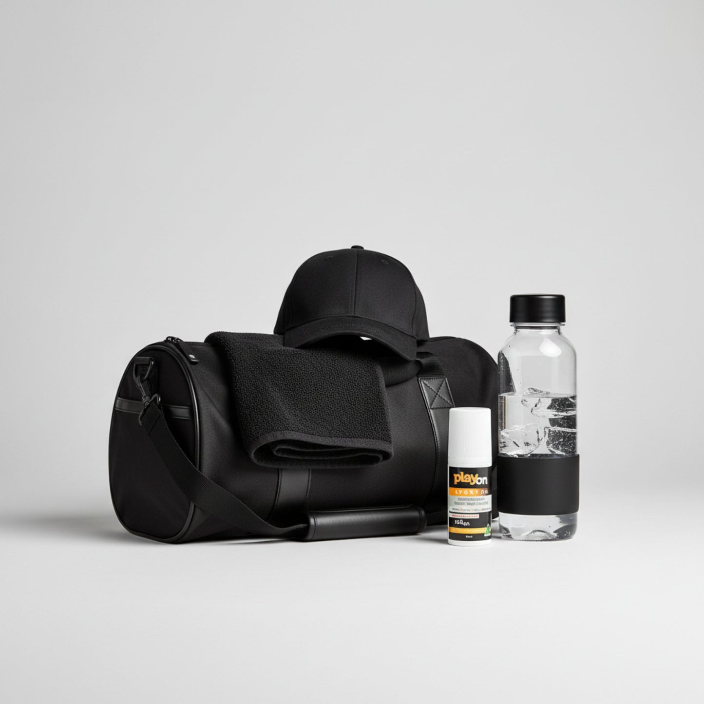 Black duffel bag with a cap, water bottle, towel and playon roll on on a light grey background.