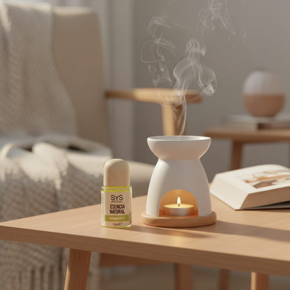 Aromatherapy oil burner with a candle and sys bergamot essence bottle on a table in a cozy room.