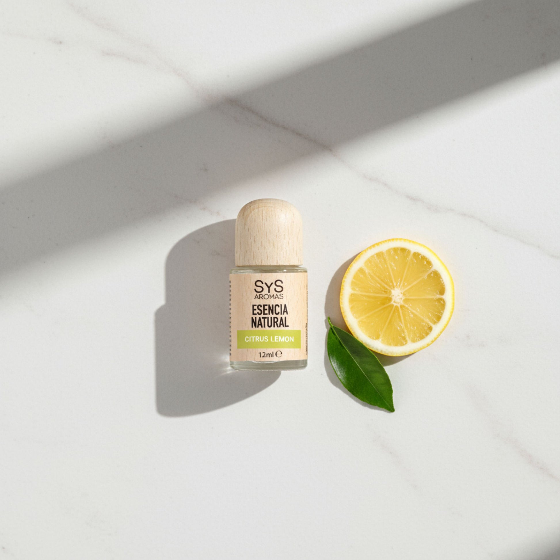 Citrus Lemon Essential oil on a white surface with a lemon slice and leaf.