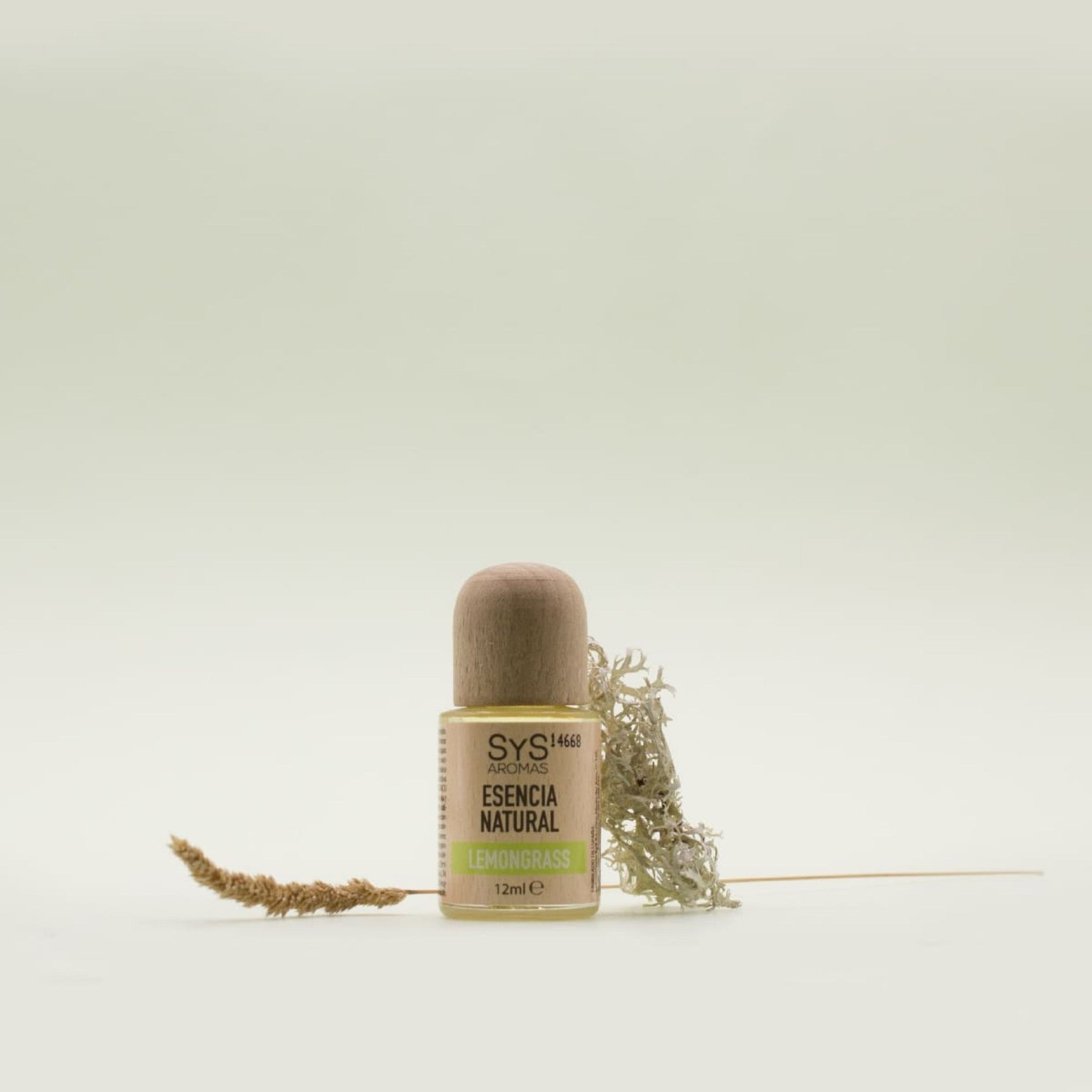 Lemongrass Essential Oil Bottle labelled with 'Natural Essence' with a dried plant on a light background