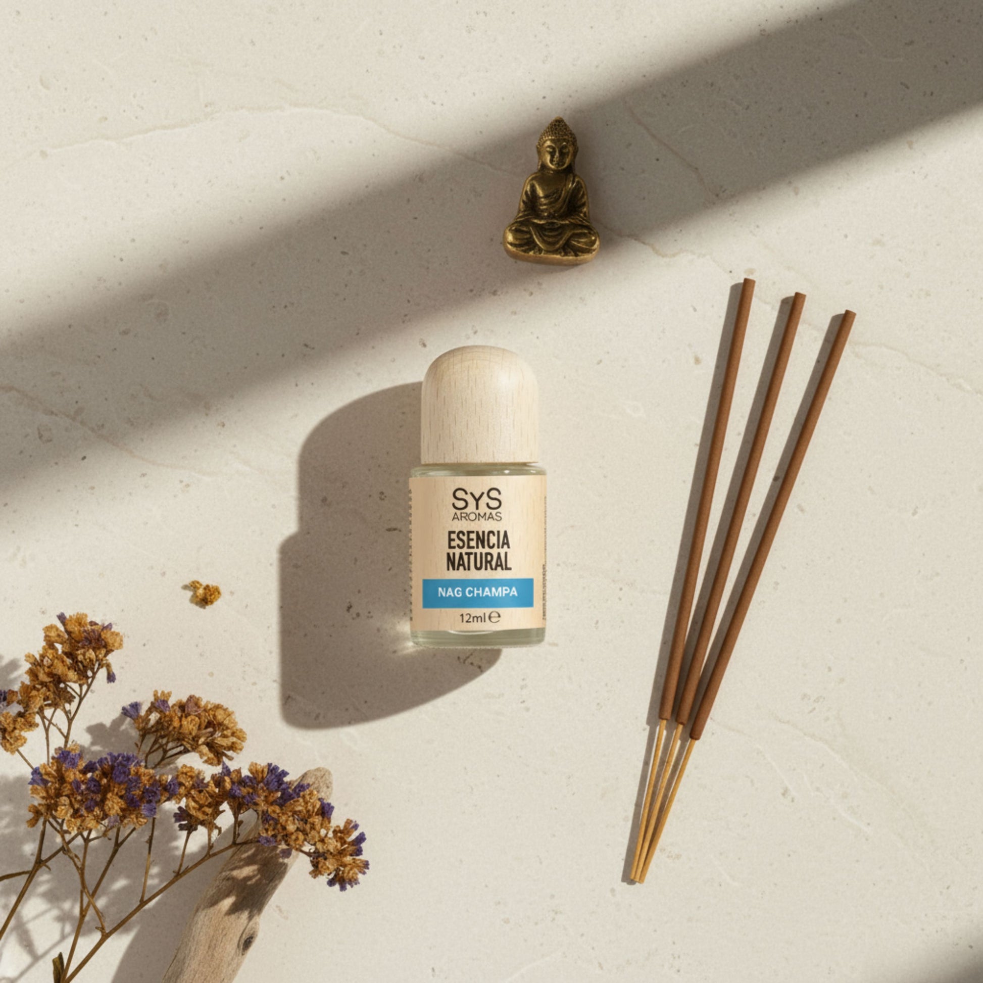 Nag champas essentail oil bottle with incense sticks on a light surface with dried flowers and a small buddha statue.