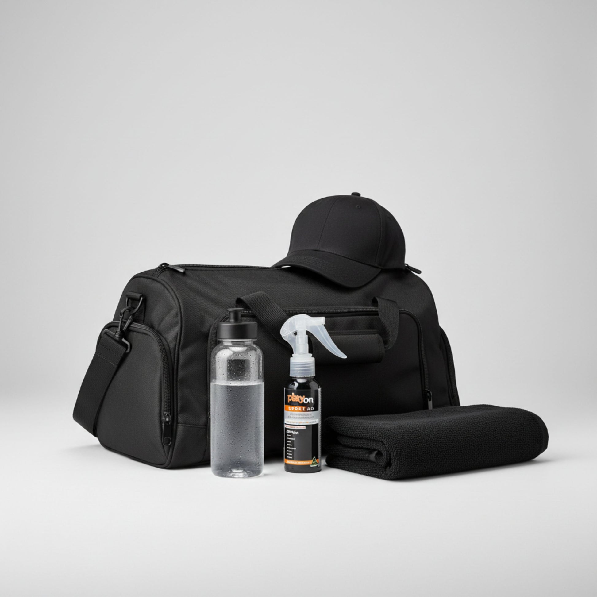 Black duffel bag with a cap, water bottle, towel and playon spray 80ml on a light grey background.