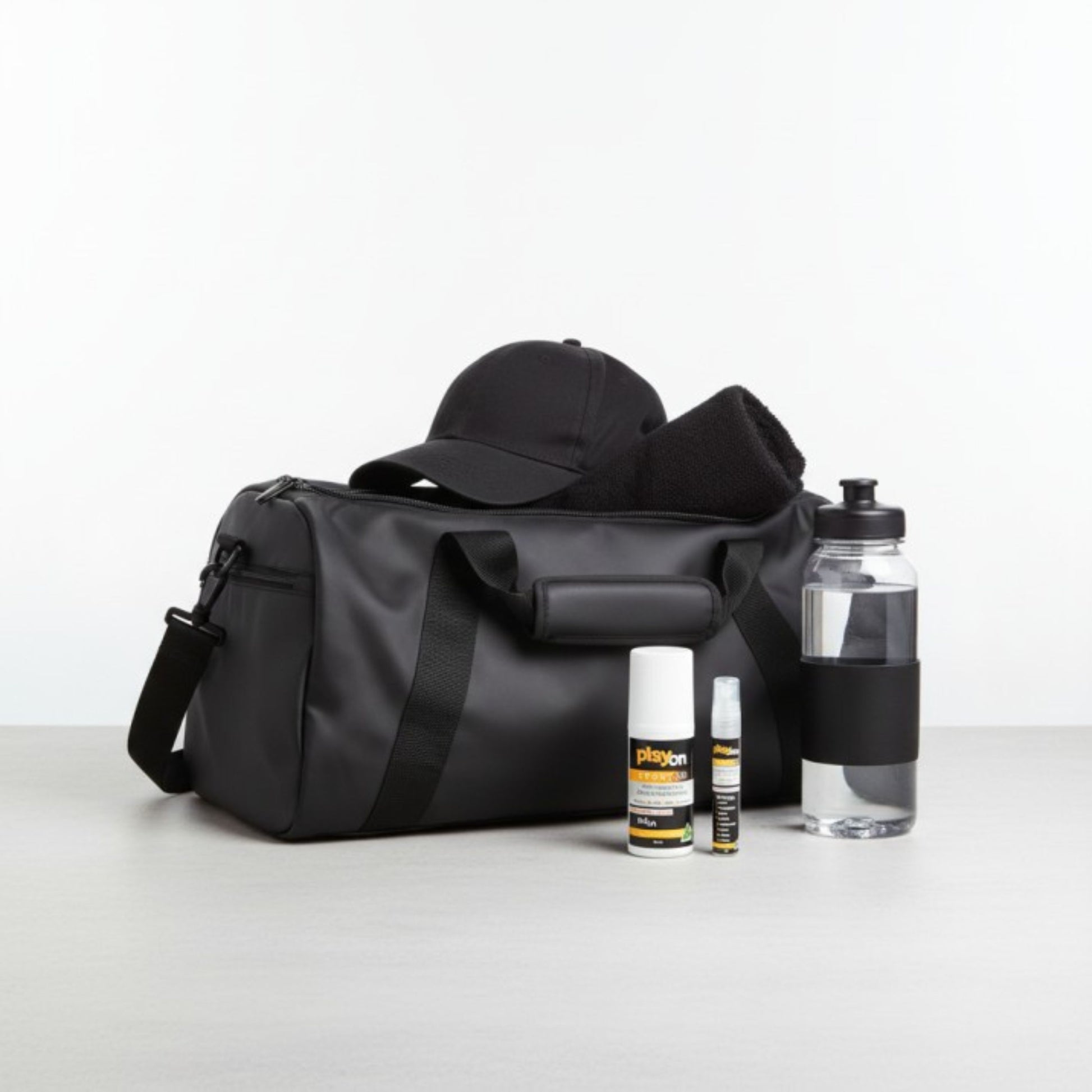 Black duffel bag with a cap, bottles, and playon travel pack - playon roll on and playon mini on a light grey background.