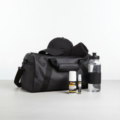Black duffel bag with a cap, bottles, and playon travel pack - playon roll on and playon mini on a light grey background.